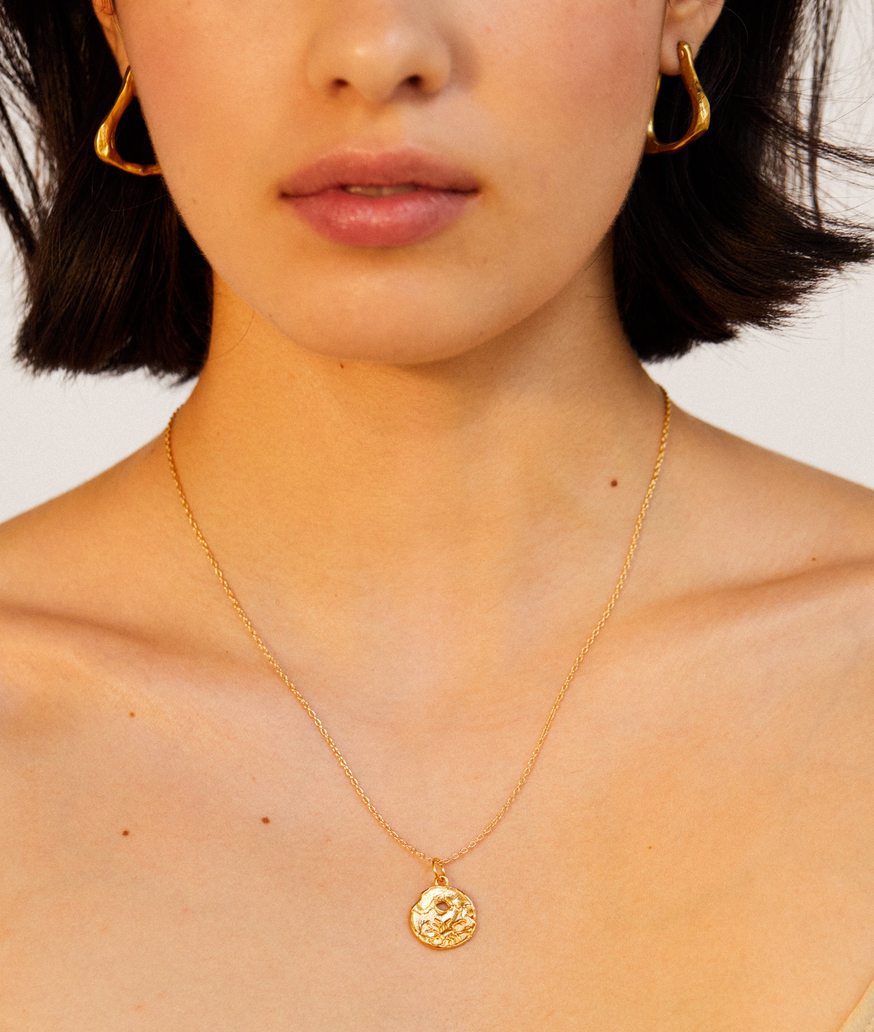 detail of model wearing Alighieri Gold Plated Scorpio Zodiac Necklace Medallion