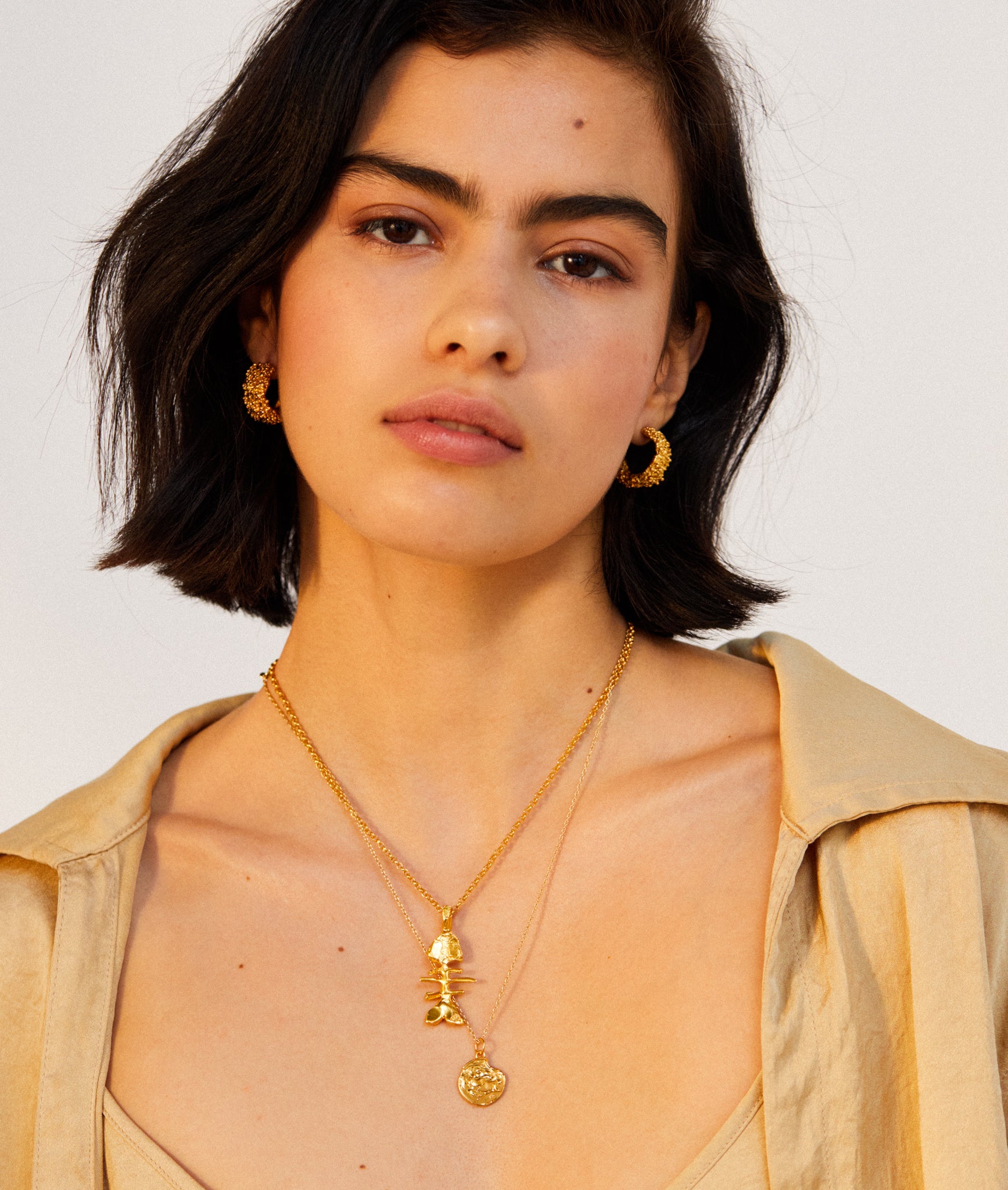 Model wearing Alighieri Gold Plated Pisces Zodiac Medallion Necklace  Layered