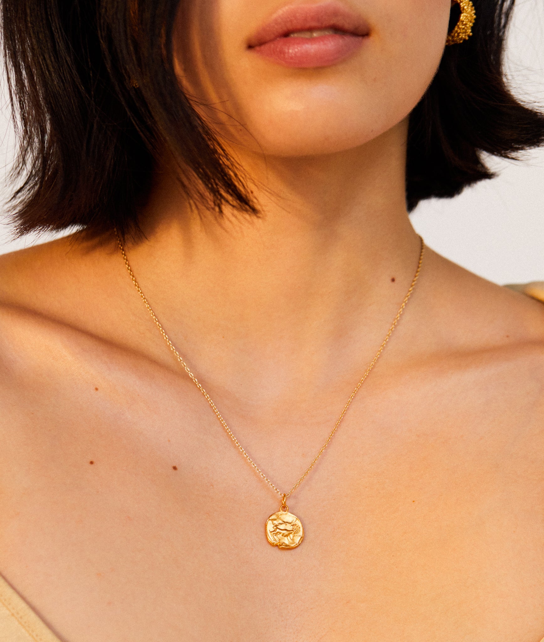 detail of model wearing Alighieri Gold Aries Zodiac Necklace Medallion